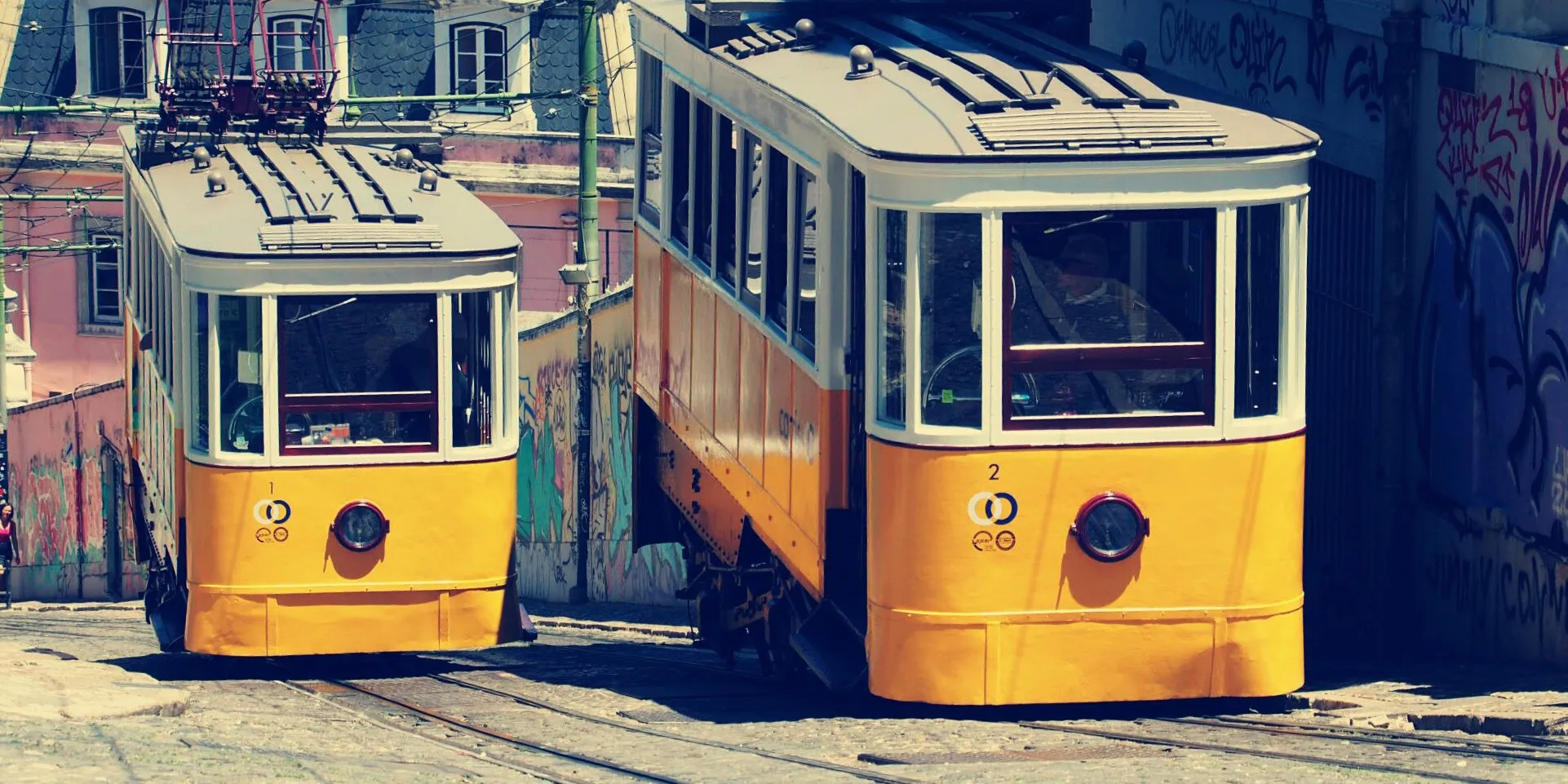 Two Lisbon funicular cars on sloped street.