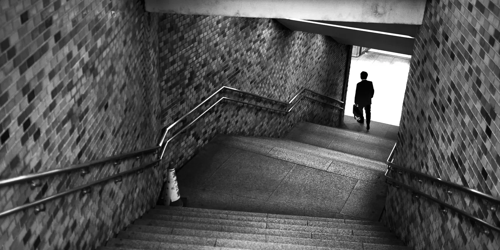 Man descends stairs in Tokyo subway.